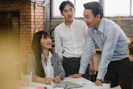 Multiracial group of young creative people in casual wear meeting brainstorming ideas about new paperwork project colleagues working together planning success strategy enjoy teamwork in small officeの写真素材