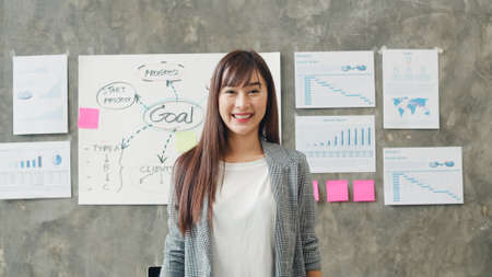 Portrait of successful beautiful executive businesswoman smart casual wear looking at camera and smile, happy in modern office workplace. Young Asia lady stand relax in contemporary coworking space.の写真素材