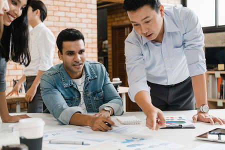Multiracial group of young creative people in smart casual wear discussing business brainstorming meeting ideas mobile application software design project in modern office. Coworker teamwork concept.の写真素材