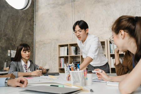 Multiracial group of young creative people in casual wear meeting brainstorming ideas about new paperwork project colleagues working together planning success strategy enjoy teamwork in small officeの写真素材