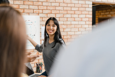 Multiracial group of young creative people in casual wear meeting brainstorming ideas about new paperwork project colleagues working together planning success strategy enjoy teamwork in small officeの写真素材