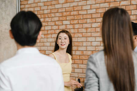 Asia businessmen and businesswomen meeting brainstorming ideas conducting business presentation project colleagues working together plan success strategy enjoy teamwork in small modern office.の写真素材