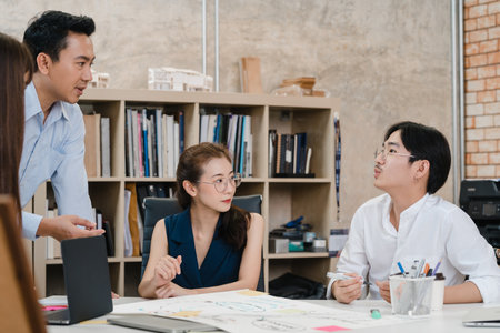 Happy young Asia businessmen and businesswomen meeting brainstorming ideas about new paperwork project colleagues working together planning success strategy enjoy teamwork in small modern office.の写真素材