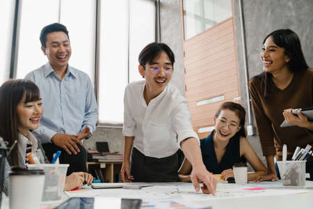 Multiracial group of young creative people in casual wear meeting brainstorming ideas about new paperwork project colleagues working together planning success strategy enjoy teamwork in small officeの写真素材