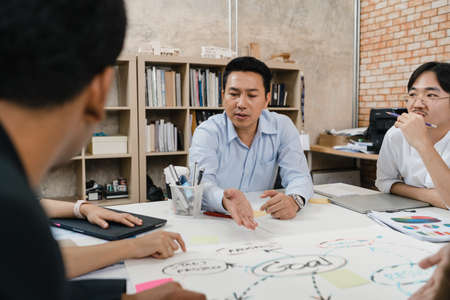 Multiracial group of young creative people in smart casual wear discussing business brainstorming meeting ideas mobile application software design project in modern office. Coworker teamwork concept.の写真素材