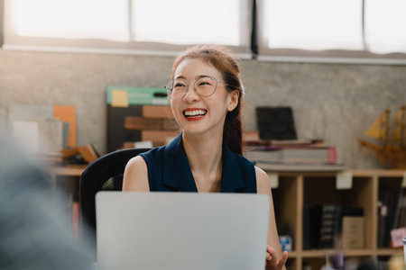 Happy young Asia businessmen and businesswomen meeting brainstorming ideas about new paperwork project colleagues working together planning success strategy enjoy teamwork in small modern office.の写真素材