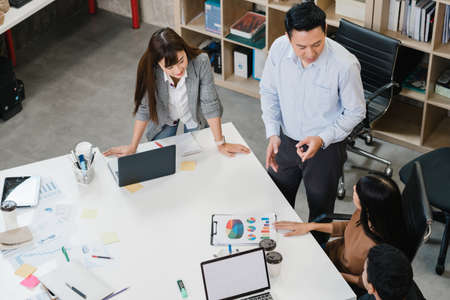 Multiracial group of young creative people in casual wear meeting brainstorming ideas about new paperwork project colleagues working together planning success strategy enjoy teamwork in small officeの写真素材