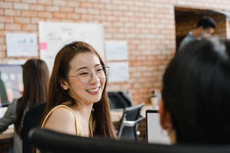 Asia businessmen and businesswomen meeting brainstorming ideas conducting business presentation project colleagues working together plan success strategy enjoy teamwork in small modern office.の写真素材