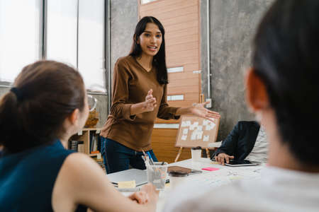 Asia businessmen and businesswomen meeting brainstorming ideas conducting business presentation project colleagues working together plan success strategy enjoy teamwork in small modern office.の写真素材