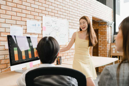 Asia businessmen and businesswomen meeting brainstorming ideas conducting business presentation project colleagues working together plan success strategy enjoy teamwork in small modern office.の写真素材