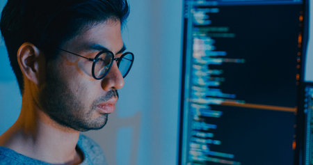 Closeup young adult Asia male freelance typing write prompt AI bot IT app smart program nomad, video game, terminal with coding language, designer, big data center on desktop computer in night office.の写真素材
