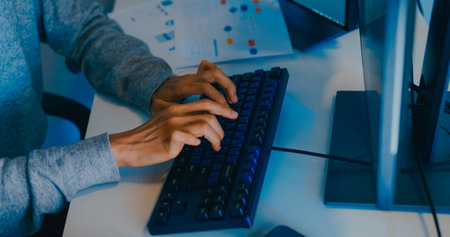 Closeup young adult Asia male freelance typing write prompt AI bot IT app smart program nomad, video game, terminal with coding language, designer, big data center on desktop computer in night office.の写真素材