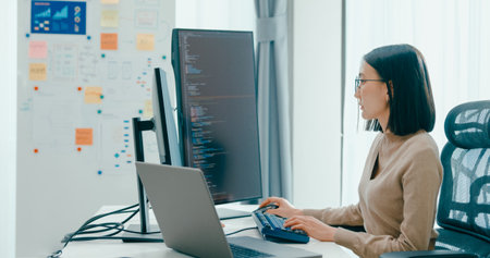 Young adult Asia female freelance eyeglasses typing write prompt AI bot IT app smart program nomad, video game, terminal with coding, user interface, designer, big data center on desktop computer.の写真素材