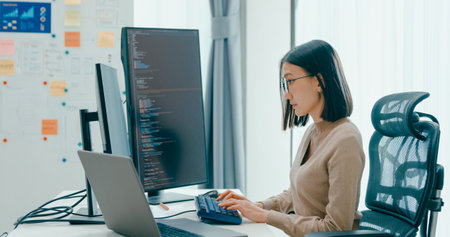 Young adult Asia female freelance eyeglasses typing write prompt AI bot IT app smart program nomad, video game, terminal with coding, user interface, designer, big data center on desktop computer.の写真素材