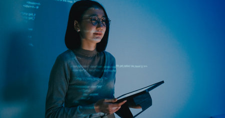 Adult Asian female software developer and mentor discusses strategy and plans with executives, focusing on writing prompts for AI bots and IT applications. The setting includes a projected slideshow with code.の写真素材