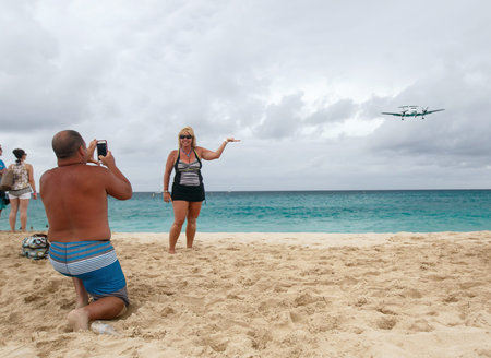 Saint Martin, Dutch Antilles, March 25, 2017: People on Maho beach are posing for pictures with airplanes that are landing on the adjacent airport.のeditorial素材
