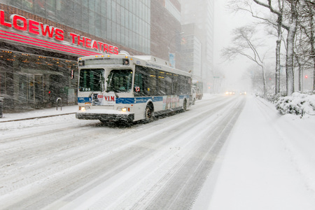 New York, February 9, 2017:  An MTA bus is driving by a Loews Theaters on Broadway near 68th street during a heavy snowfall.のeditorial素材