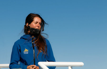 Reykjavik, Iceland, August 20, 2017: A female whale watching tour guide is speaking into her...