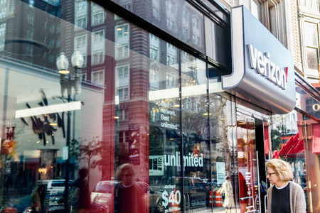 Boston, October 28, 2017: Woman is passing by a Verizon store and looking inside through the window.のeditorial素材