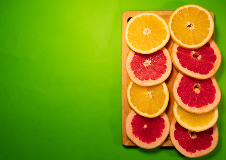 Top view, flat lay, macro. Many slices colorful citrus on a black background. Fruits lined up in the...