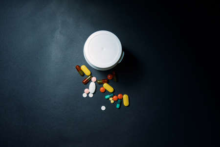 Medical bottles and medication pills spilling out on to pastel blue background. Top view with copy space. Healthcare, pharmacy, medicine conceptの写真素材