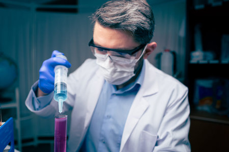 Young Scientist Checking Test Tubes In The Lab. Man Wears Protective Goggles
