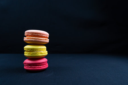 Colorful stack of macaroons isolated on plain black background. Copyspaceの写真素材