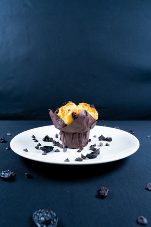 Chocolate, raisin chips and chocolate raisin muffin on a orange plate. black background.の写真素材