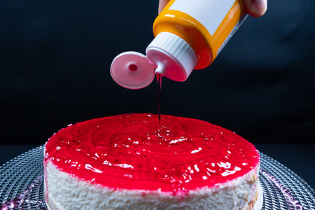 Cheesecake with berries on black background. Pouring sauce on chessecakeの写真素材