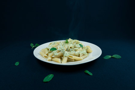 Pesto penne pasta dish on a black backgroundの写真素材