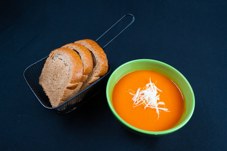 Tomato soup with basil, and bread in a bowl. Dark background.の写真素材