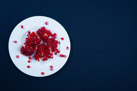 Fresh tasty sweet peeled pomegranate with red seeds on dark black background, top view, healthy food fruitsの写真素材