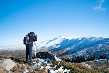 Man in the mountain photographing the mountain covered with snowの写真素材