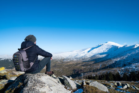 Young man sitting on the edge of the mountain and enjoy the winter landscape.
