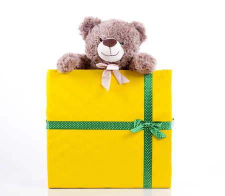 teddy bear in gift box yellow color with a green ribbon with polka dots. peeps. Surprise gift. White background.の写真素材