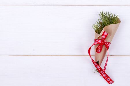 Christmas Background - fir branches wrapped in kraft paper and tied with a red ribbon on a white wooden background. Christmas conceptの写真素材