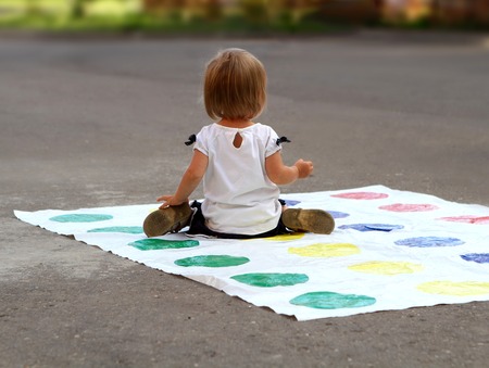 baby little girl playing in the street, sitting back. twist gameの写真素材