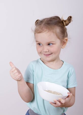 little girl with a plate of oat flakesの写真素材