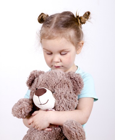 little blond girl hugging a teddy bearの写真素材