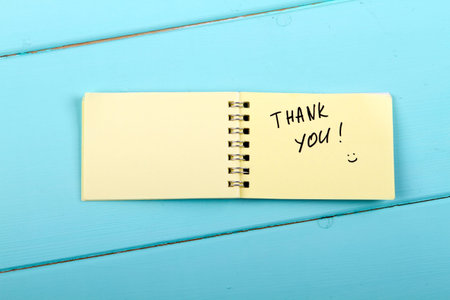 Thank You, A spiral Notepad that has the words Thank You over a distressed wood turquoise backgroundの写真素材