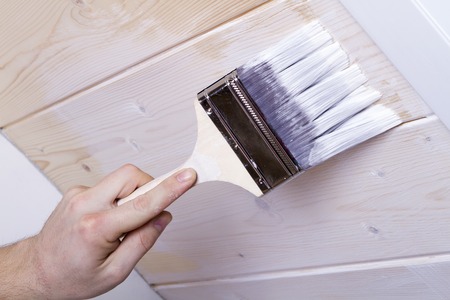 man's hand holding a brush and color white bunk in the mansardの写真素材