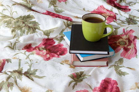 Green mug with tea or coffee in bed with bedding with floral print diary with a pencil or pen note thoughts dreamsの写真素材