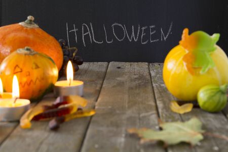 Halloween inscription on a black chalkboard chalk white, surrounded by candles celebration attributes pumpkin marmalade wormsの写真素材
