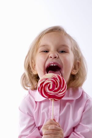 little girl with great pleasure have striped big lollipopの写真素材