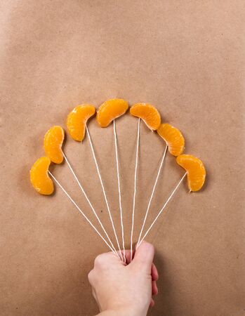 slices of mandarin in conjunction as balloons. hand holds the strings like beadsの写真素材