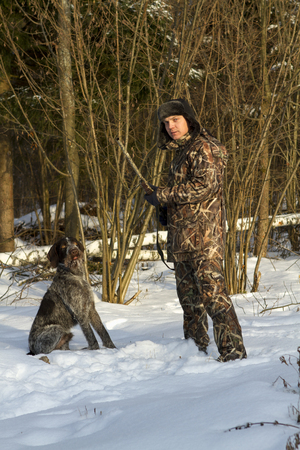 Man in camouflage with a gun and hunting drathaar.の写真素材