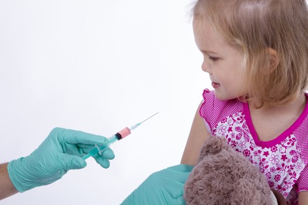 Doctor holds an injection vaccination little girl. she scerd. child is afraid and scaredの写真素材