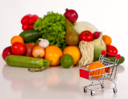 healthy fruits and vegetables in the background is blurred. foreground grocery cart with a tangerine. Isolated on white.の写真素材
