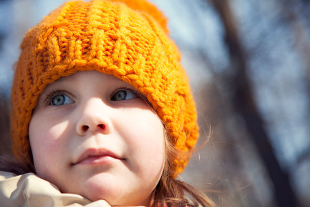 Portrait baby girl in knitted orange hat, blue eyes, pretty. Beautiful, beloved. close-up. early...