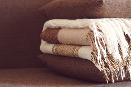 Plaids and pillows on the couch in a pile, brown shadesの写真素材